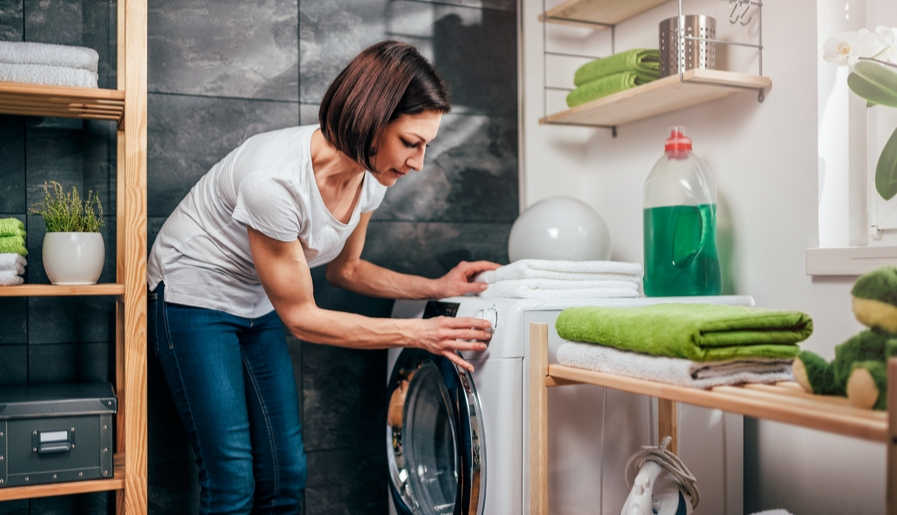 Woman putting sheets and pillowcases in the washing machine