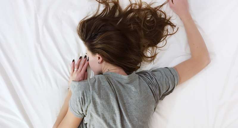 Woman lying on her stomach sleeping on white crisp sheets