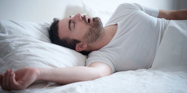 Man lying on his bed snoring while sleeping