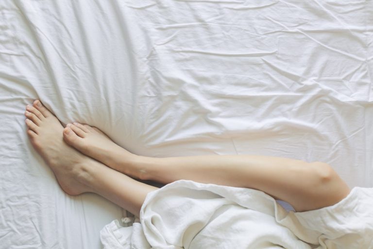 Woman in bed asleep keeping feet outside the covers to cool off