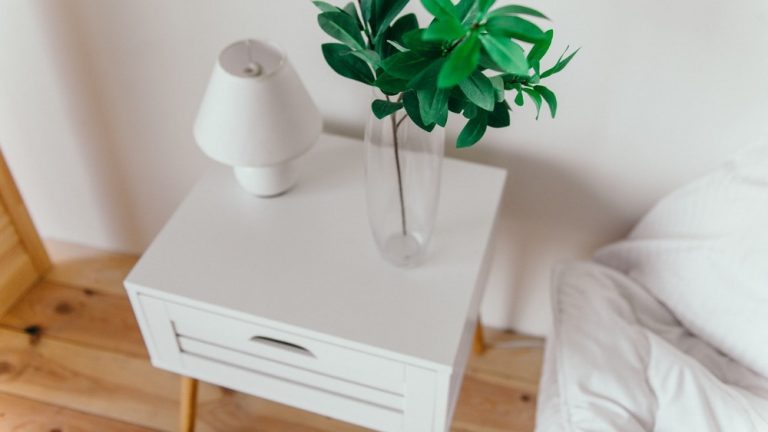 A single white bedside table near a bed