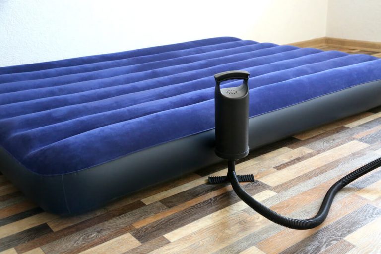 Air bed inflatable mattress and foot pumper on the floor in a bedroom.