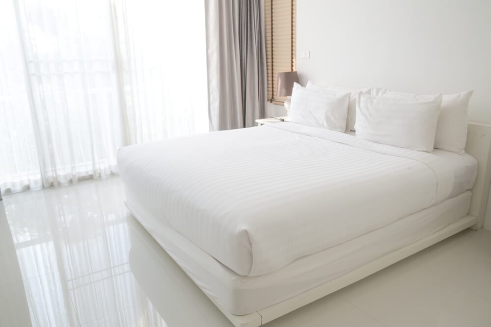 A white bed in a white bedroom with a white bed frame