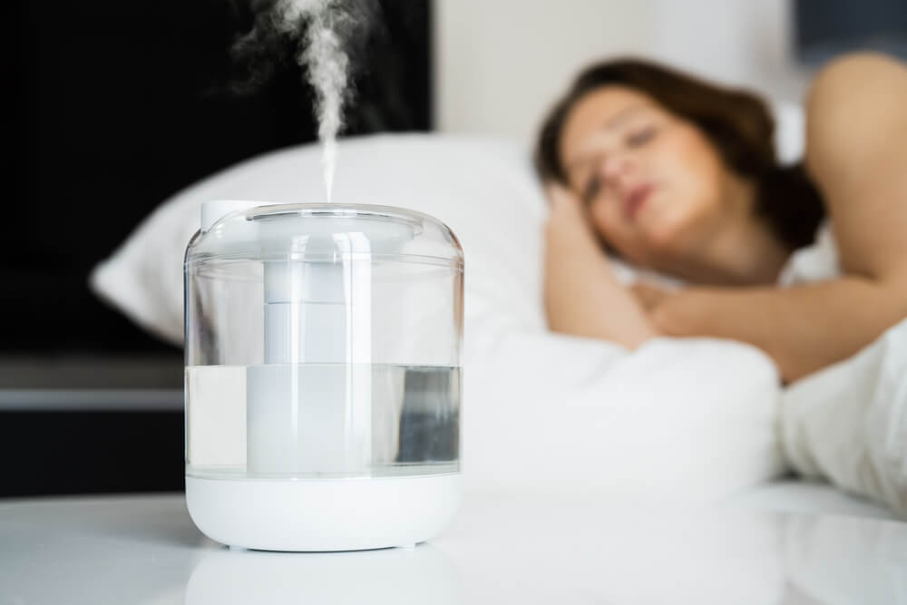 Home Air Humidifier Device In Bedroom Near Woman Sleeping