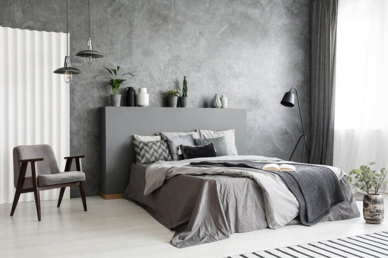 Modern grey bedroom interior with big bed with grey sheets, pillows and linen.