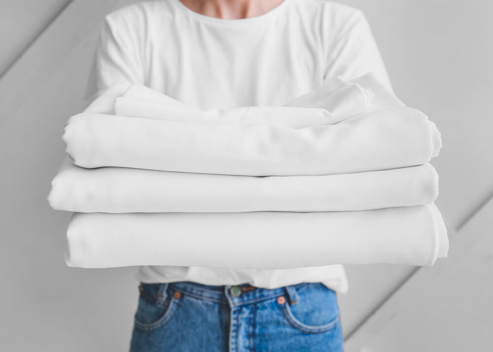 A stack of clean white bed sheets