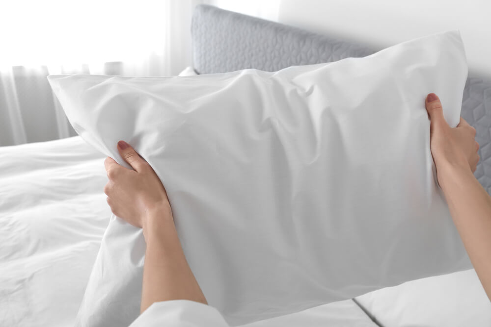 A woman fluffing a pillow