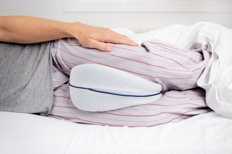 Man in bed sleeping on his side with a knee pillow