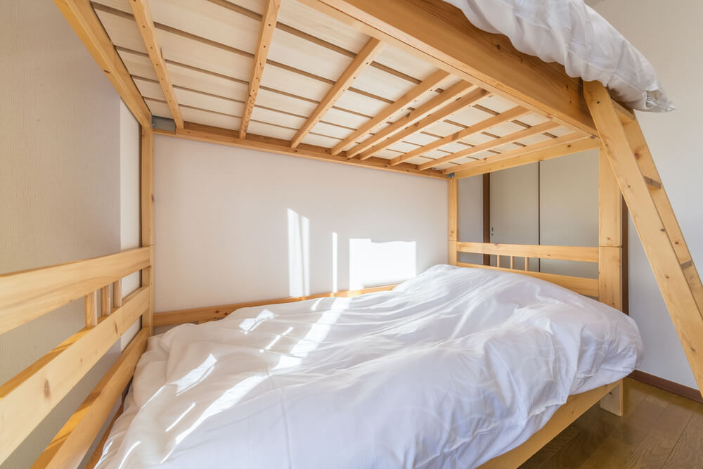 A loft or bunk bed with white bedding